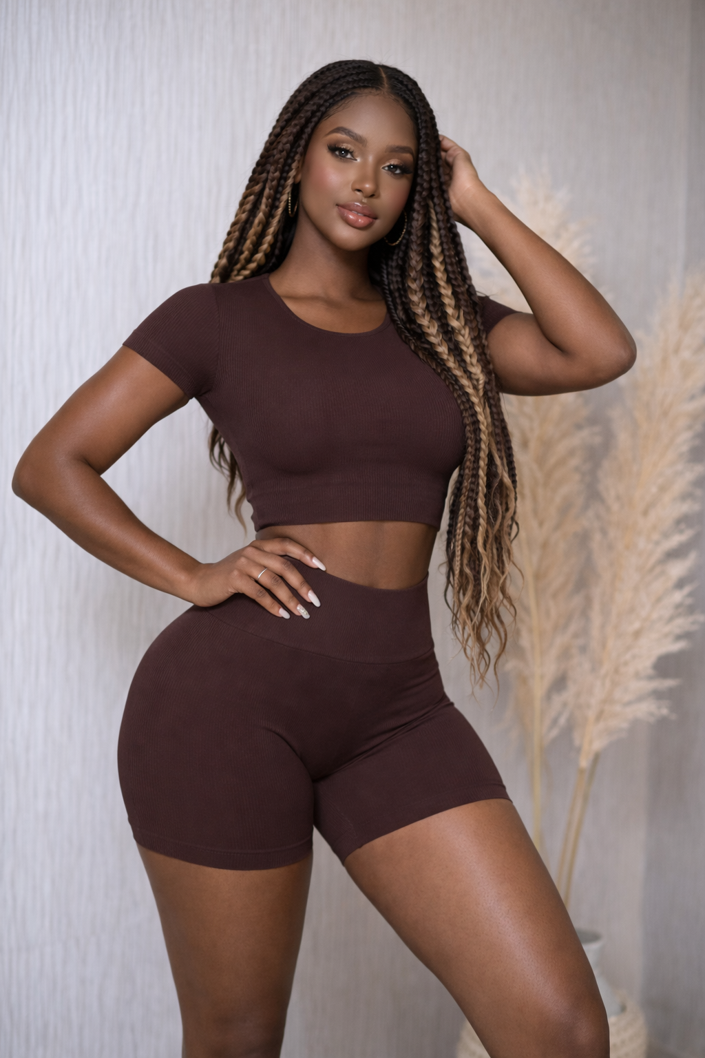Woman wearing a brown athletic outfit posing against a neutral background