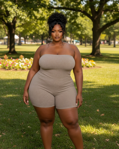 Woman in a beige strapless romper standing in a park with trees and flowers in the background