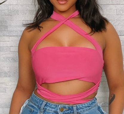Person wearing a bright pink halter top with cut-out design against a light wooden panel background